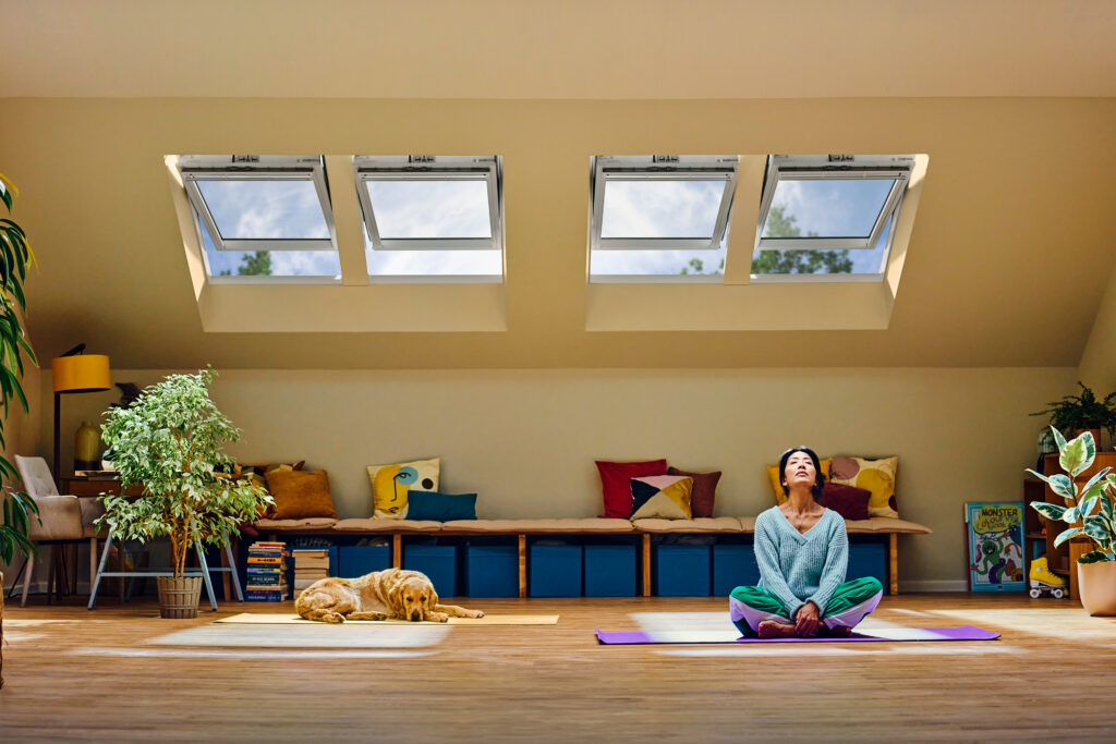 žena sa psom meditira ispod prozora u potkrovlju 